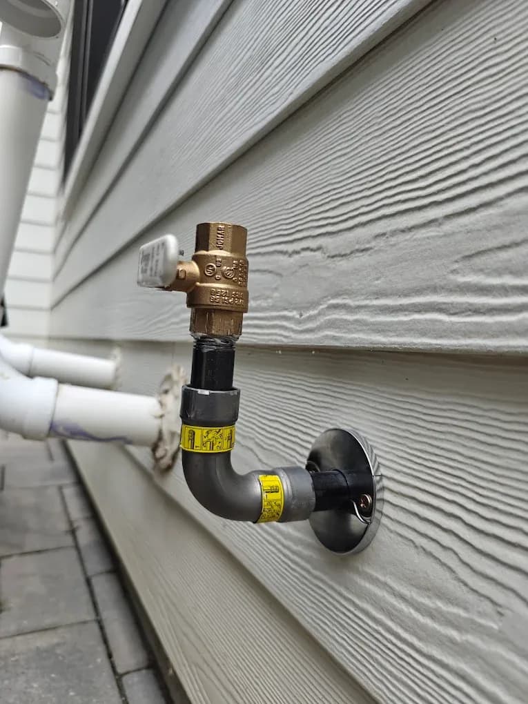A brass backflow prevention assembly mounted on the exterior wall of a northern New Jersey home