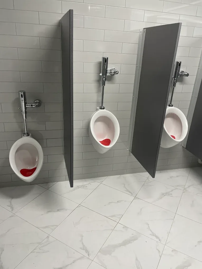 Commercial restroom urinals with flush valves and privacy partitions in a northern New Jersey building