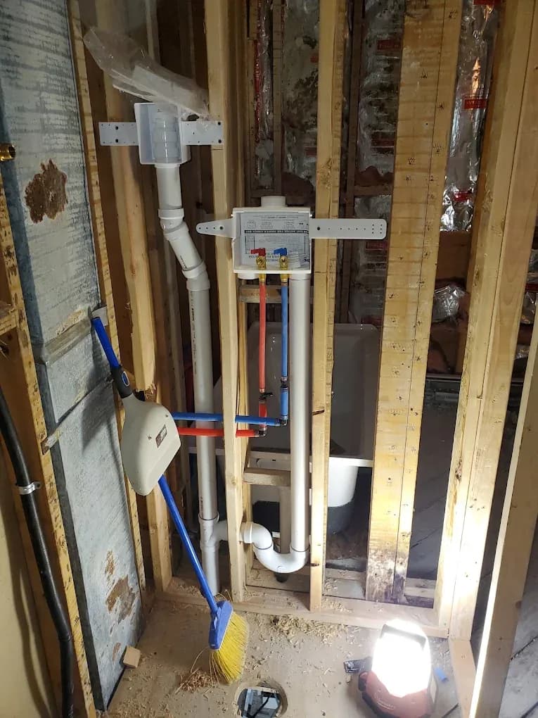 Rough-in plumbing in an open stud wall: PVC drain stack, PEX supply lines and a shower valve set ready for inspection