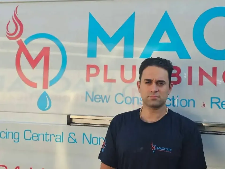 Morey Katzourin, Owner & NJ Master Plumber at Maccabi Plumbing & Heating, standing beside a branded company truck in northern New Jersey