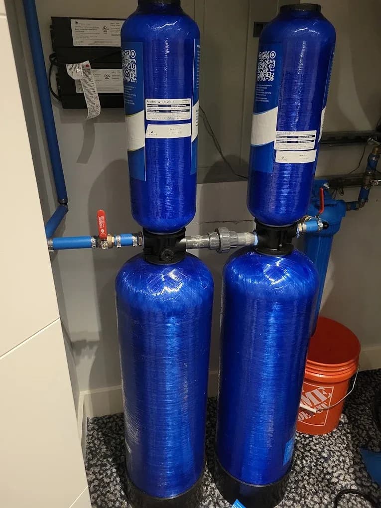 A pair of whole-house water treatment tanks plumbed in blue PEX in a northern New Jersey utility room
