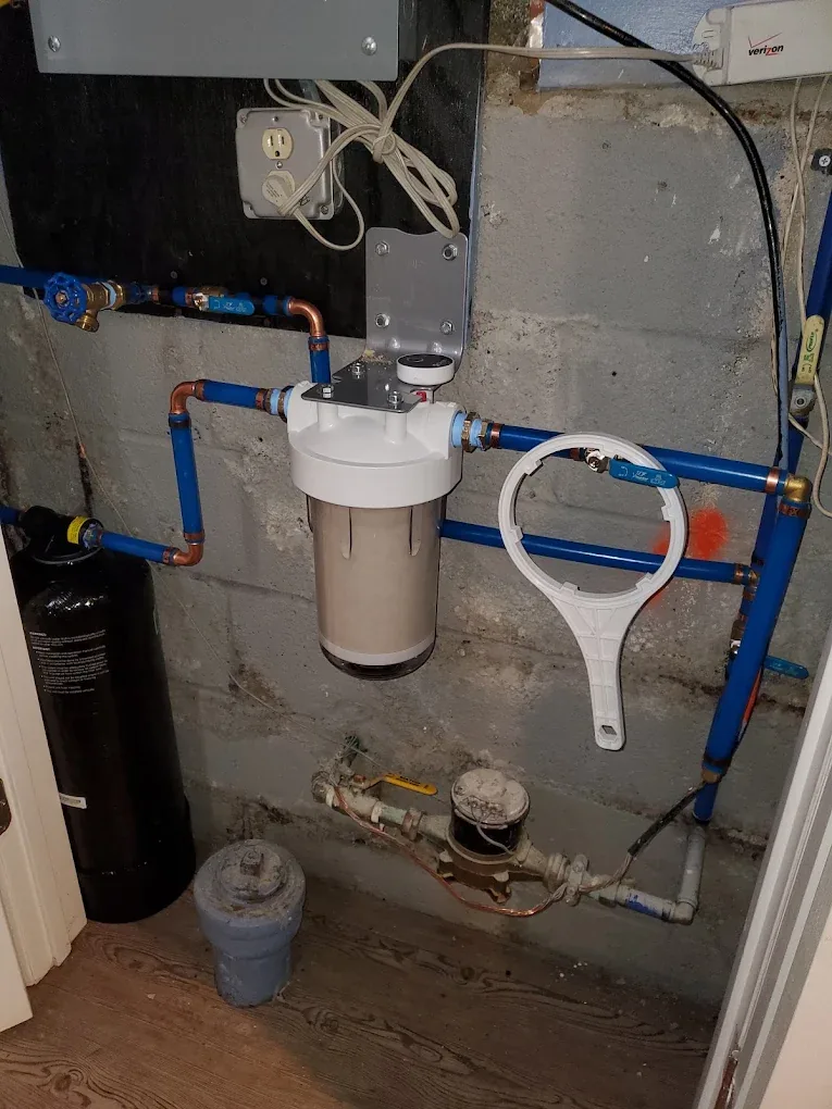 A whole-house filter housing and water meter on the incoming service line in a northern New Jersey basement
